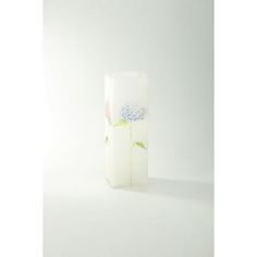 a white vase with blue and pink flowers on the outside, sitting against a white background