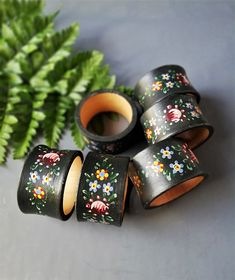 four rolls of black painted wooden tape with flowers on them next to a green plant