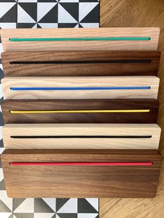 four different colored pencils sitting on top of a wooden board next to a black and white checkered floor