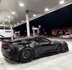 a black sports car parked in front of a gas station