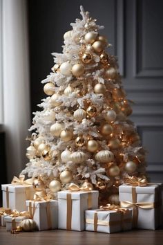 a white christmas tree with gold ornaments and presents on the floor in front of it