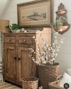 a wooden cabinet sitting next to two baskets filled with flowers