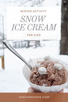 a person holding up a cup filled with ice cream and marshmallows in the snow