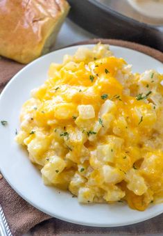 scrambled eggs on a white plate with bread in the background