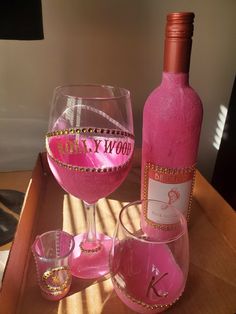 a pink wine bottle sitting next to two glasses on top of a wooden table,