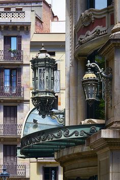 an ornate light fixture on the side of a building next to other buildings and windows