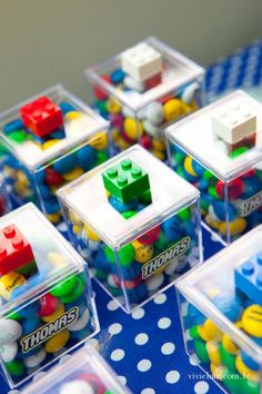 legos are arranged in plastic containers on a blue and white polka dot tablecloth