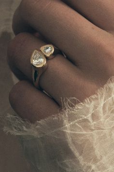 a woman's hand with two gold rings on top of her arm and one diamond ring in the middle