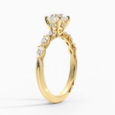 a yellow gold engagement ring with an oval cut diamond center and side stones on the band