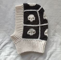 a black and white knitted sweater with skulls on the front is laying on a bed