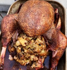 a roasting pan with a whole chicken on it's side and stuffing in the middle