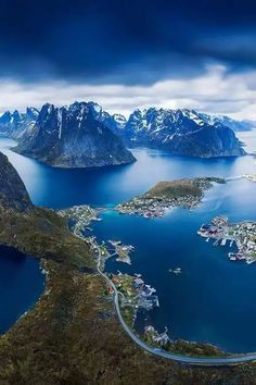 an aerial view of the mountains, water and town in norway with snow capped mountains