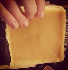 a person holding a piece of cheese in their hand