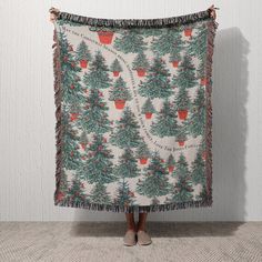 a woman standing in front of a christmas tree blanket