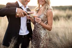 a man and woman standing next to each other holding wine glasses