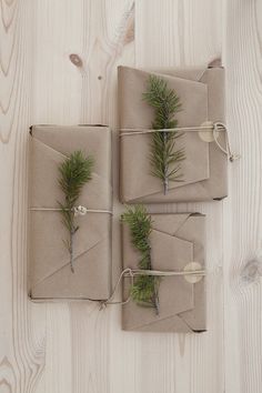 three wrapped presents are tied with twine and pine needles