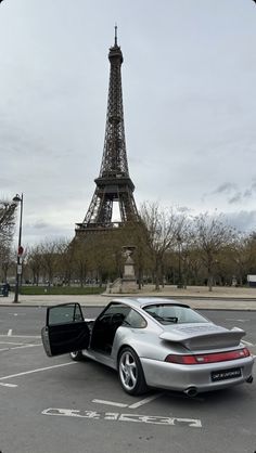 a silver car parked in front of the eiffel tower