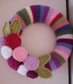 a crocheted wreath with flowers is hanging on the wall