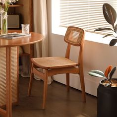 a wooden chair sitting in front of a window next to a table with flowers on it