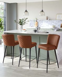 three chairs are sitting at the bar in this kitchen with marble counter tops and gray walls