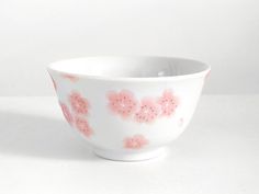 a white bowl with pink flowers painted on the outside and inside, sitting on a table