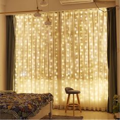 a bedroom with lights on the curtains and a stool in front of it, next to a bed