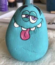 a blue rock with a tongue sticking out and eyes drawn on it's face