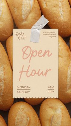 a close up of bread rolls with a paper sign on it that says open hour