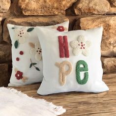 two pillows with embroidered numbers on them sitting next to a brick wall and stone fire place