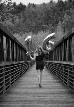 a woman is walking across a bridge with balloons in the shape of numbers on it