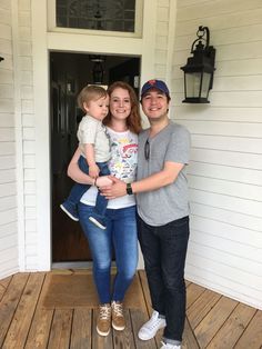 a man and woman standing on a porch holding a baby