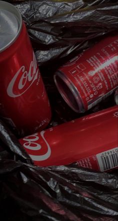 coca - cola cans are sitting in a black plastic bag