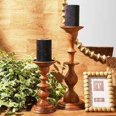 two wooden candlesticks sitting on top of a table next to a potted plant