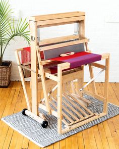 a weaving machine sitting on top of a wooden floor next to a potted plant