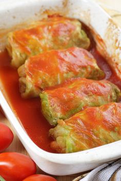 stuffed cabbage and tomatoes in a white dish on a wooden table next to fresh cherry tomatoes