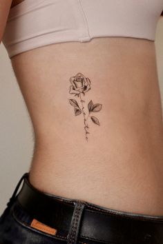 a woman's stomach with a rose tattoo on her belly and the bottom part of her abdomen