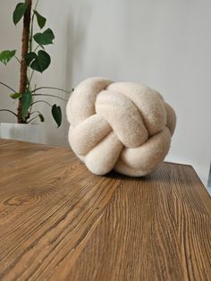 a ball of wool sitting on top of a wooden table next to a potted plant