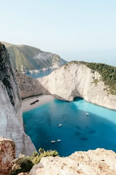 boats are floating in the blue water near white cliffs