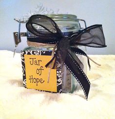 a jar filled with some kind of stuff on top of a white blanket and black ribbon