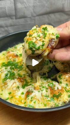 a person is dipping some food into a bowl with broccoli and cheese on it