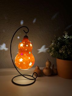 an orange light bulb sitting on top of a table next to a potted plant