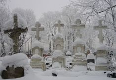 a cemetery covered in snow with many headstones and crosses on the top of them