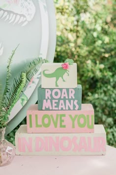 a cake made to look like dinosaurs on top of each other with the words roar means i love you in pink and green