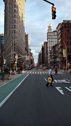 a person crossing the street at an intersection with traffic lights and buildings in the background