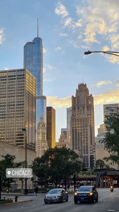 cars are driving down the street in front of tall buildings with skyscrapers behind them