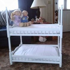 a white bunk bed with two stuffed animals on the bottom shelf and a lamp next to it