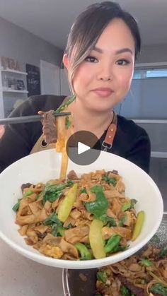 a woman is holding up a plate of food with chopsticks in her hand