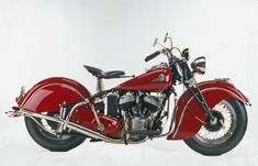 a red motorcycle parked on top of a snow covered ground in front of a white background