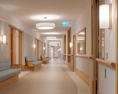 an empty hospital hallway with blue chairs and lights on the ceiling, and white walls