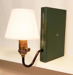 a lamp that is next to a book on a shelf with it's light turned on